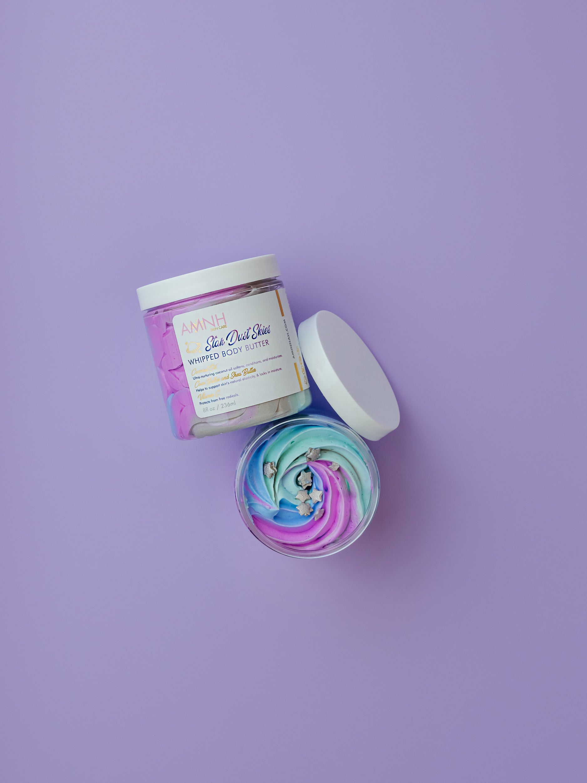 Open jar with a purple whipped swirl and the lid beside it on purple.
