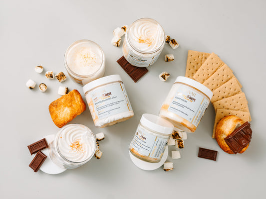Jars with marshmallows, chocolate squares and a waffle cone on grey.