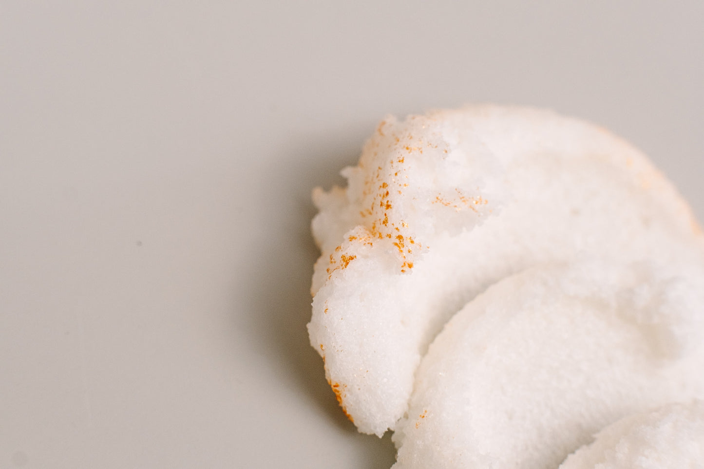 White whipped scrub swirl resting on a grey surface.