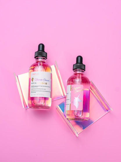 Two body oil bottles beside an iridescent prism on pink.