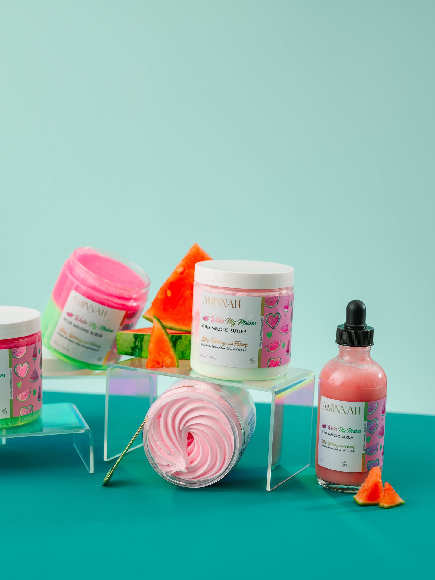 Jars and a dropper bottle with watermelon pieces on mint.