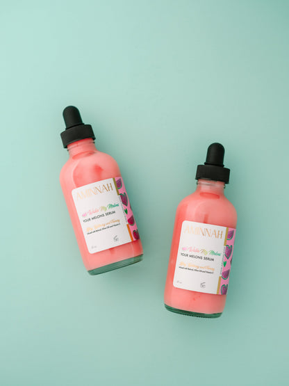Two pink serum bottles with black dropper caps on mint.