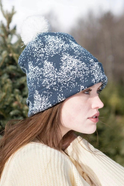 Side view of the slate blue pom pom beanie on a model outdoors