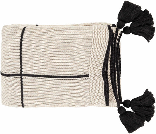 Folded cream knit cotton throw blanket with black grid lines and black tassels at the corners