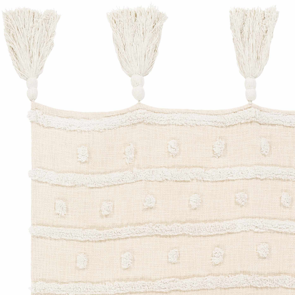 Close-up of the cream throw blanket showing tufted dots, raised stripes and three tassels with knotted tops