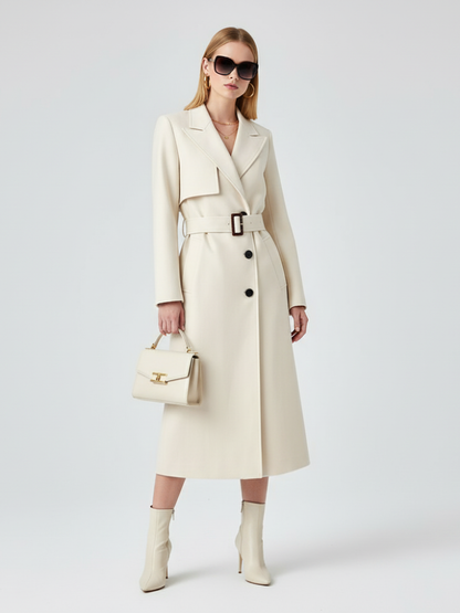 Women’s cream maxi trench coat from BYMANYC New York, shown hanging in an urban retail setting.