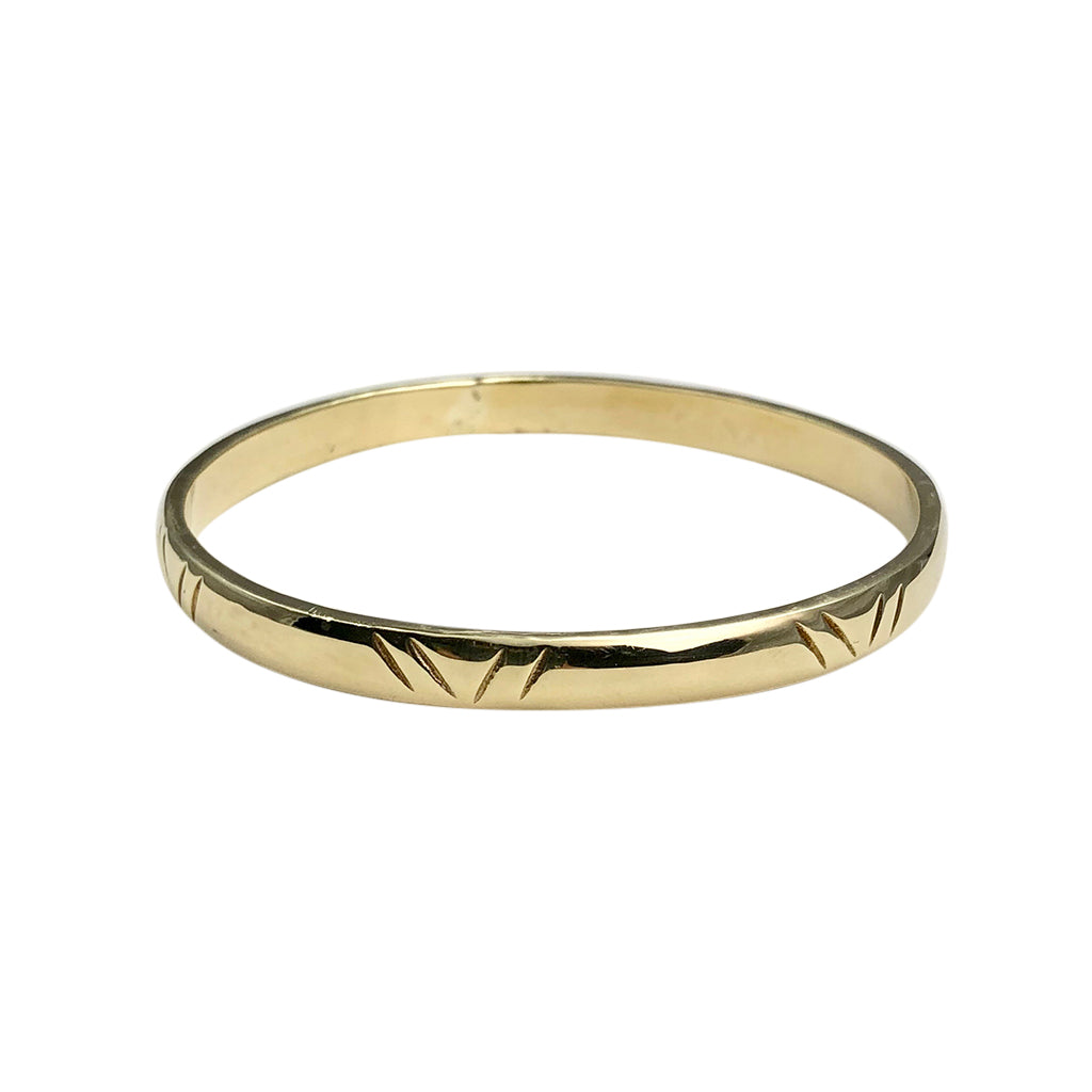 Carved brass bangle bracelet on white, with pairs of slanted notches around the band