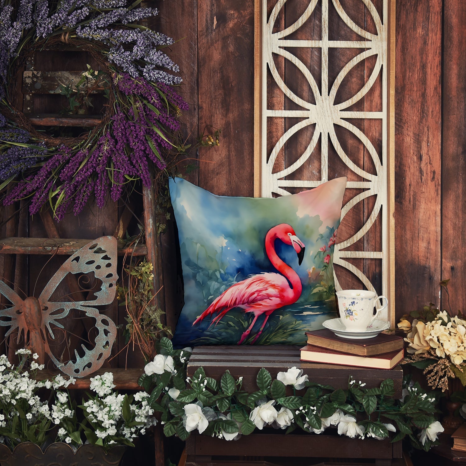 The Flamingo artwork pillow against a rustic wooden door, with lavender and white flowers around it.