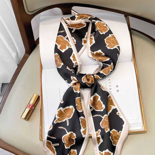 Brown Flowers colorway, a long silk scarf with caramel blooms on black and a cream edge, knotted on a book