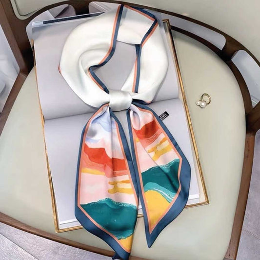 Skinny silk scarf knotted on a chair, white with coral, teal and gold painted hills and a slate blue edge
