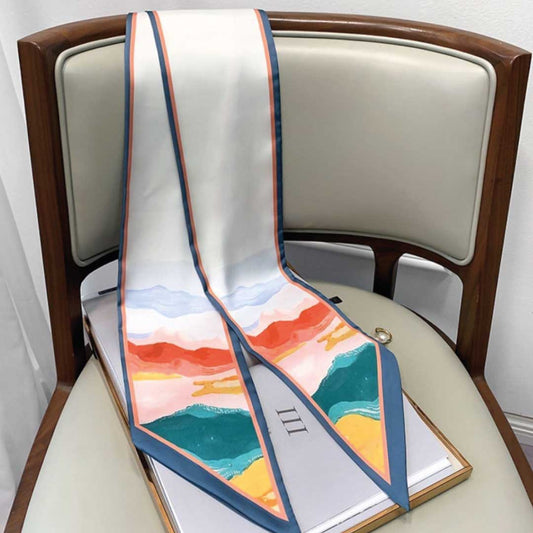 The same skinny silk scarf hanging straight, showing the full length of the coral and teal hill print