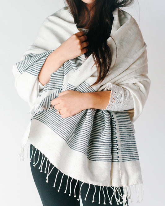Woman wrapped in the natural cotton throw with navy stripes as a shawl, knotted fringe at the hem