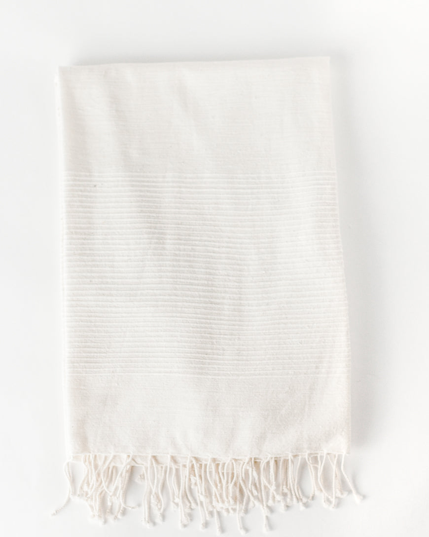 Flat view of the natural cotton throw with tone on tone stripes and knotted fringe at the bottom