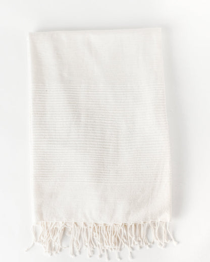 Flat view of the natural cotton throw with tone on tone stripes and knotted fringe at the bottom