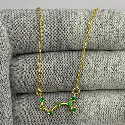 Constellation necklace with seven green tourmaline stones linked by gold tone bars over gray knit