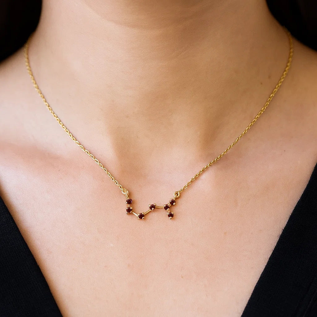 Woman in a black top wearing the constellation necklace in red garnet at the base of the neck