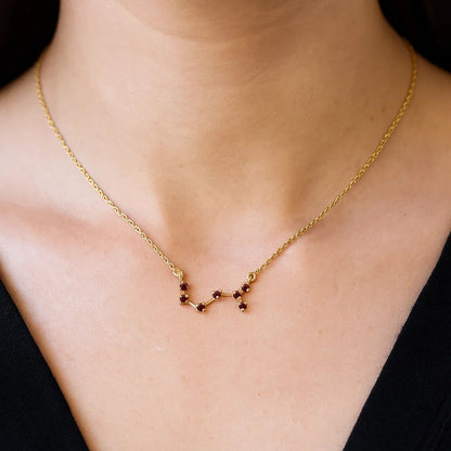 Woman in a black top wearing the constellation necklace in red garnet at the base of the neck