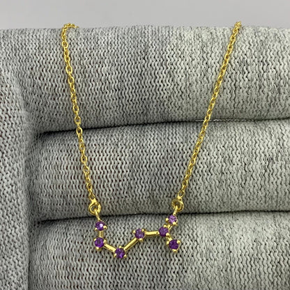 Constellation necklace with seven purple amethyst stones draped over gray knit fabric