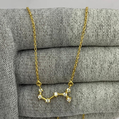 Constellation necklace with seven clear white zircon stones draped over gray knit fabric