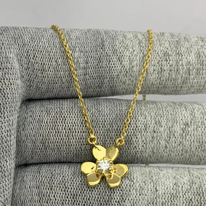 Flower necklace with a clear moissanite center draped over gray knit fabric