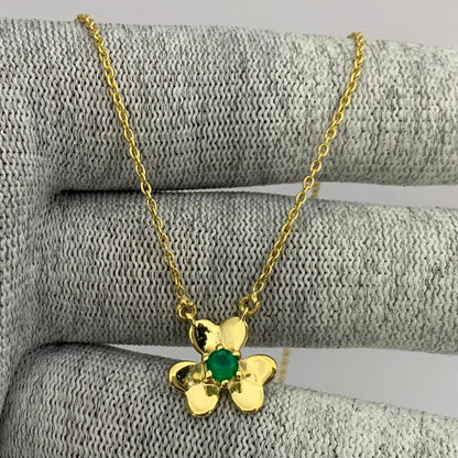 Flower necklace with a green onyx center draped over gray knit fabric