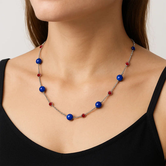 Woman in a black tank top wearing the lapis lazuli station necklace with red garnet accents at the collarbone