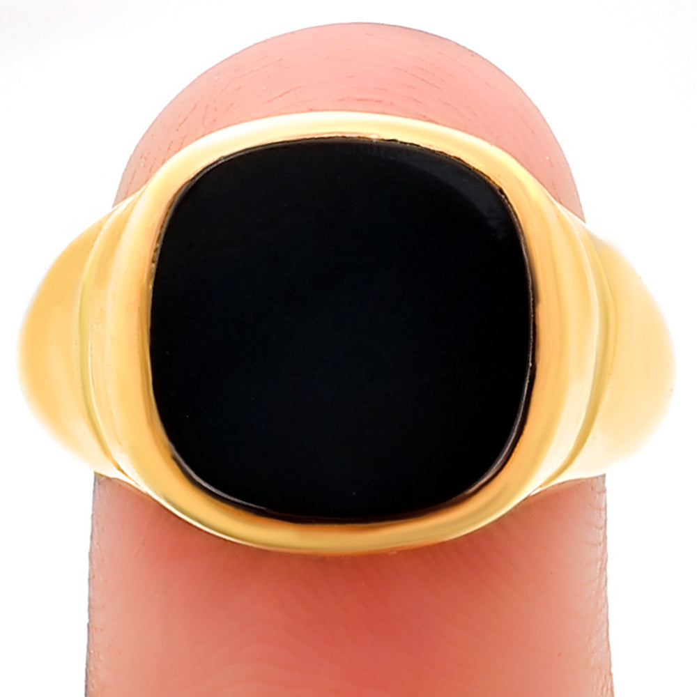 Black onyx signet ring balanced on a fingertip, cushion stone seen straight on