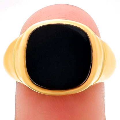 Black onyx signet ring balanced on a fingertip, cushion stone seen straight on
