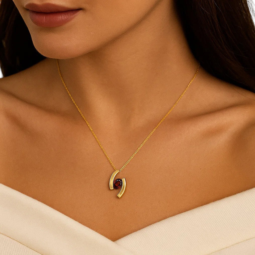 Woman wearing the curved bar pendant with an oval red garnet below the collarbone