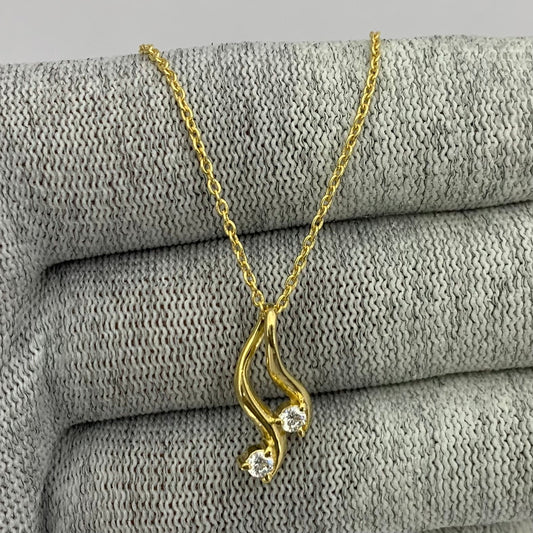 Swirl pendant with two clear white zircon stones on a gold tone chain over gray knit