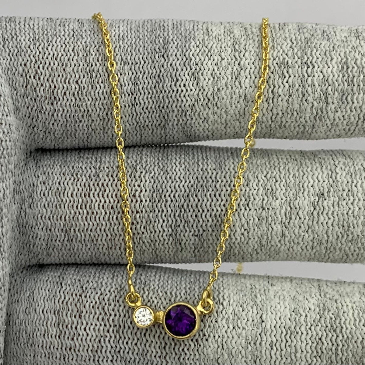 Amethyst version of the two stone necklace draped over gray knit fabric