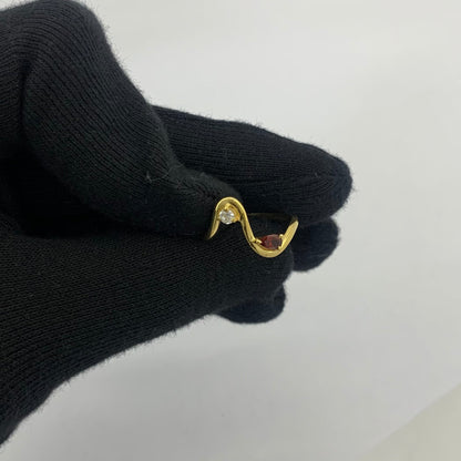 Wave ring with a pear garnet held between two gloved fingertips to show its size