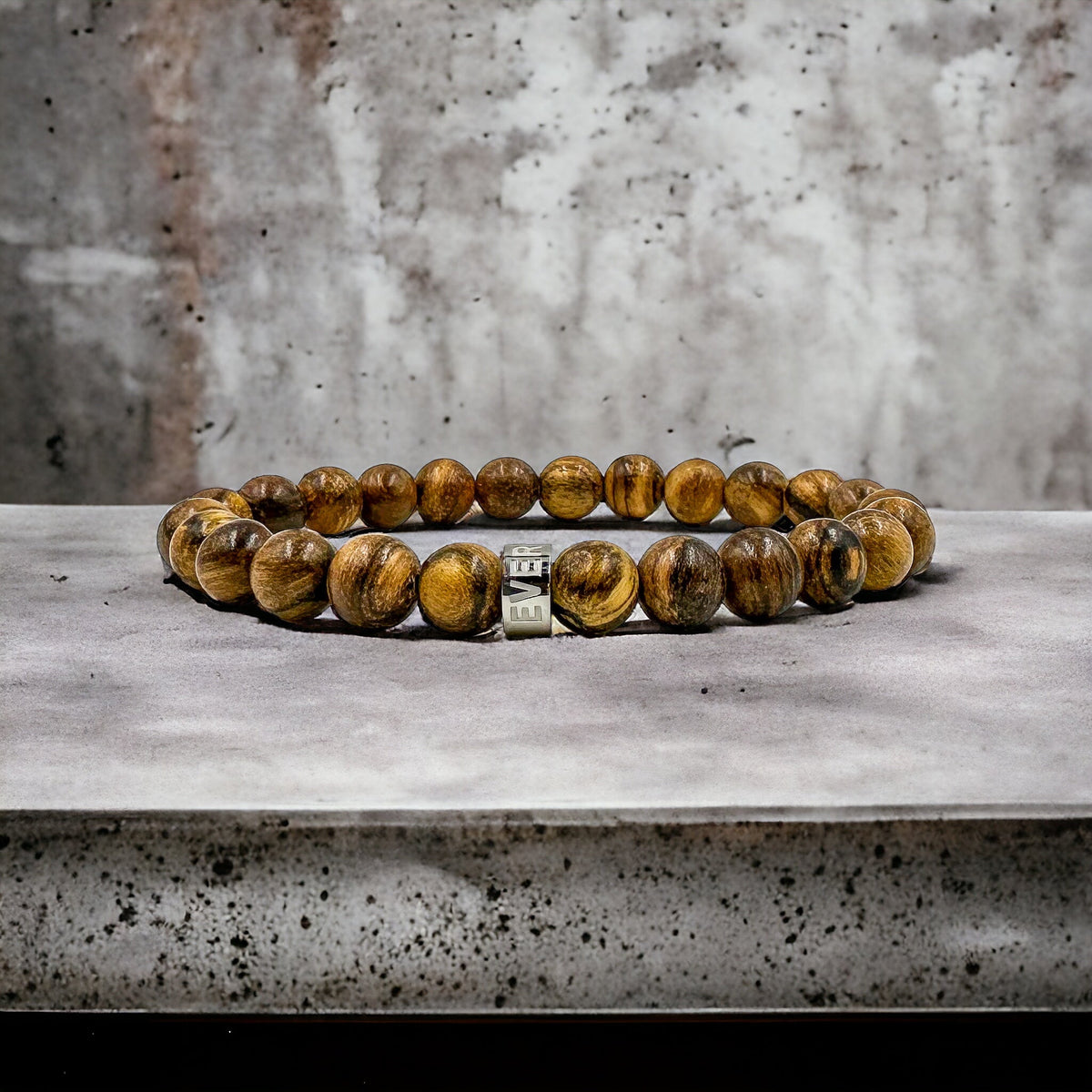 Cascade Boulderline brown sandalwood beaded bracelet, shown on a concrete surface
