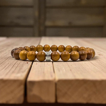 Cascade Cinder Rock padauk wood beaded bracelet, shown on a wood surface