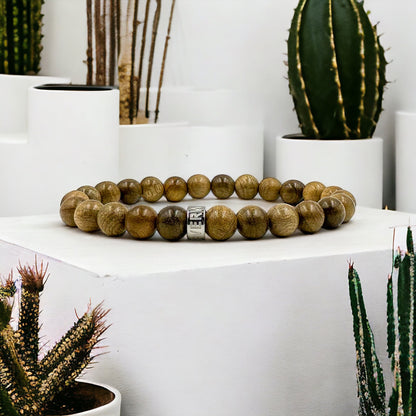 Cascade Pineforge olivewood beaded bracelet, shown on a podium beside a cactus