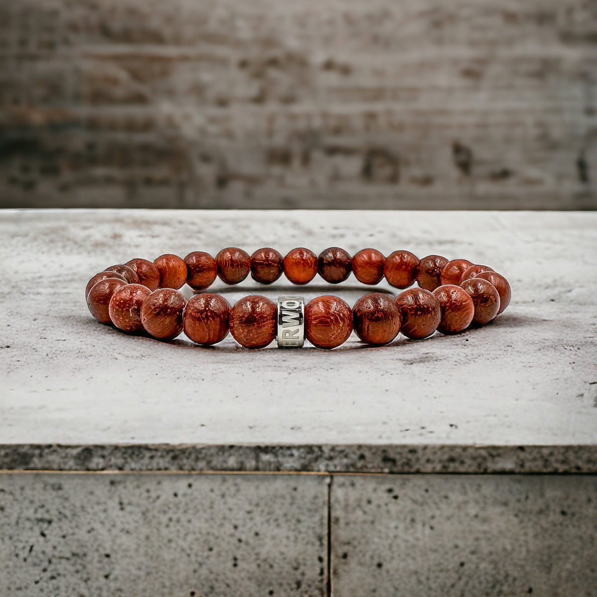 Cascade Rusthorn red rosewood beaded bracelet, shown on a concrete surface