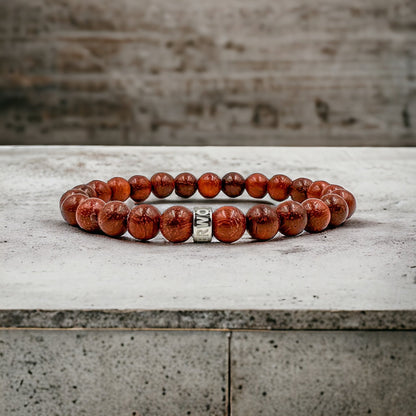 Cascade Rusthorn red rosewood beaded bracelet, shown on a concrete surface
