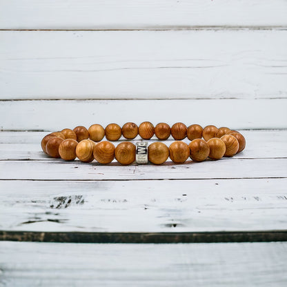 Cascade Tanglepine canary wood beaded bracelet, shown on a white wood surface
