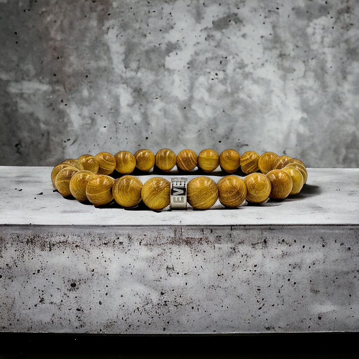 Cascade Yella Ember golden sandalwood beaded bracelet, shown on a concrete surface