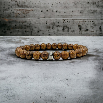 Cascade Roughcut brown zebrawood beaded bracelet, shown on a concrete surface