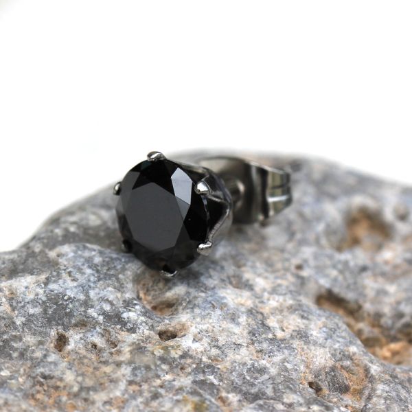 Close view of a black CZ stud in a six prong setting resting on gray stone