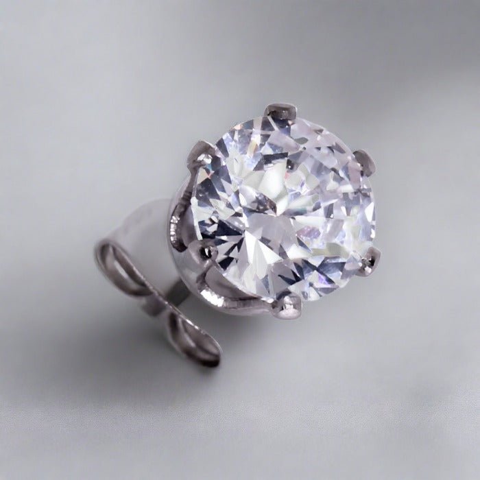 Close view of a six prong clear round CZ stud on a steel post with its clutch
