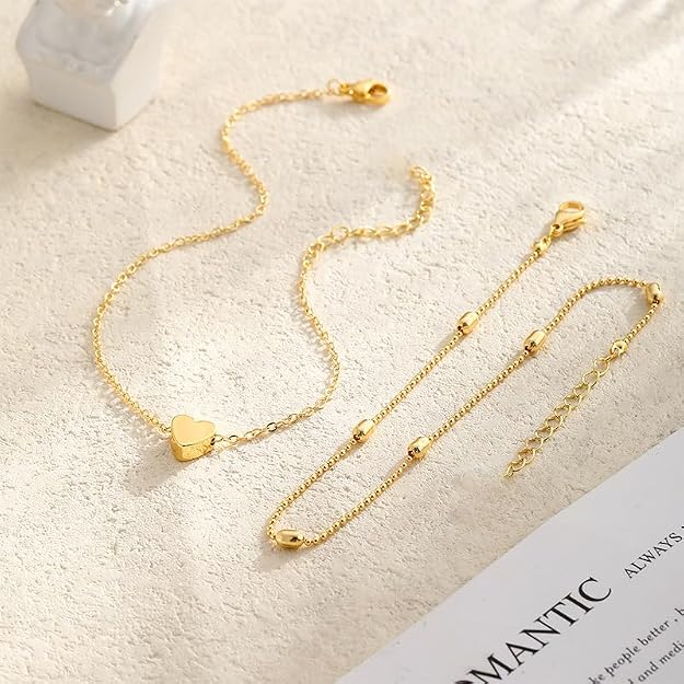 Gold tone heart anklet laid flat with its beaded upper chain, lobster clasp and extender chain