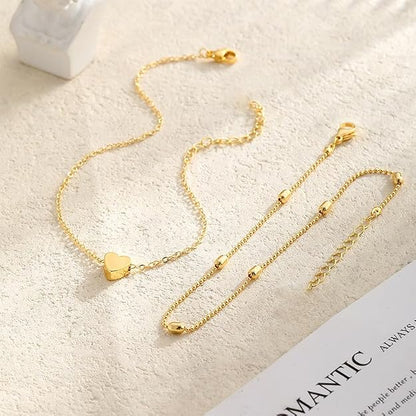 Gold tone heart anklet laid flat with its beaded upper chain, lobster clasp and extender chain