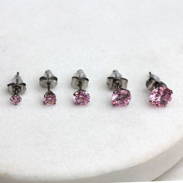 Pink CZ stud earrings in five sizes from 3mm to 7mm lined up on white stone