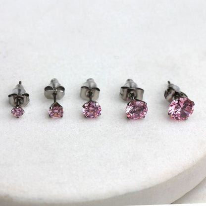 Pink CZ stud earrings in five sizes from 3mm to 7mm lined up on white stone