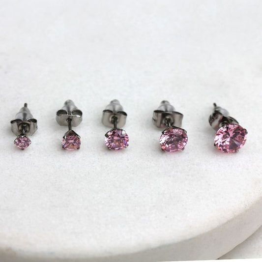 Pink CZ stud earrings in five sizes from 3mm to 7mm lined up on white stone