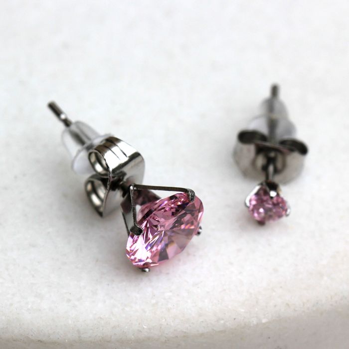 Close view of two pink CZ studs in six prong settings with clear rubber backs