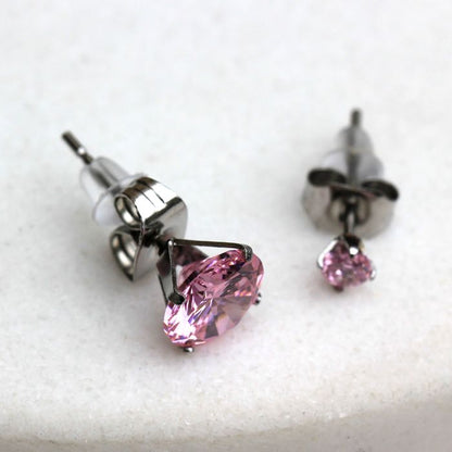 Close view of two pink CZ studs in six prong settings with clear rubber backs