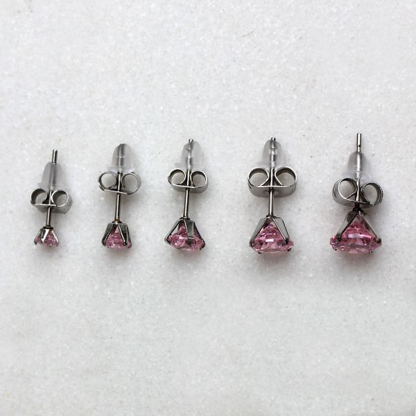 Pink round CZ studs with steel clutches in five sizes on a white surface